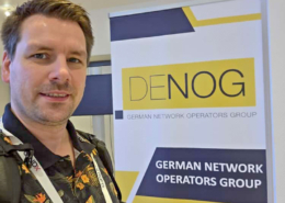 xCrew-Mitglied Stefan vor einem Roll Up des DENOG e.V.